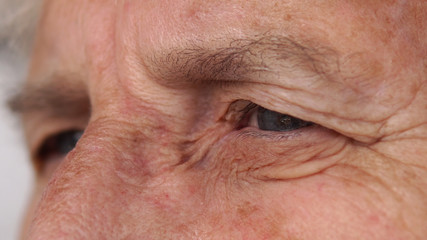 Closeup of lovely elderly woman grandmother eye looking out and blink