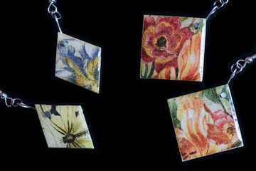 Two pairs of wooden earrings with a floral print on a dark background close up