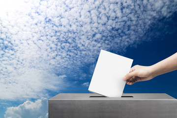 Hand holding ballot paper for election vote at blue sky background, freedom of election vote concept.