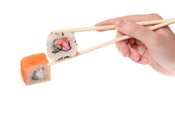 Hand holding bamboo chinese chopsticks and mouthwatering rolls, on white background. Japanese food.