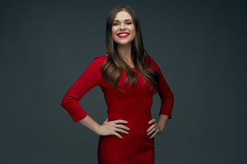 smiling woman in red dress holds hands on his hips.