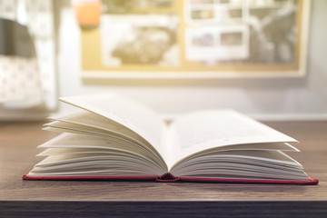 Closeup the book at wood desk with open book in class room background.