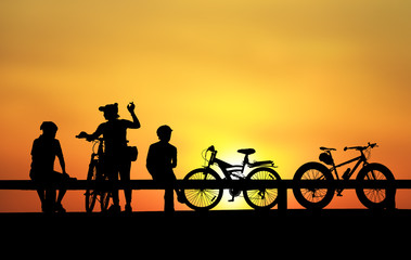 Silhouette group friend  and bike relaxing on blurry sunset background.
