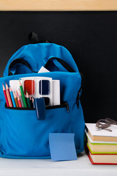 blue backpack on a black background, with a set of subjects for school