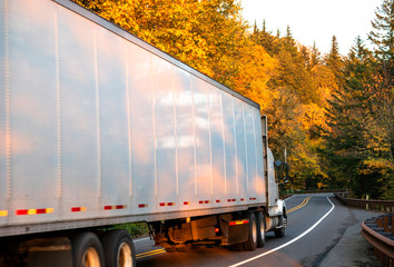Big rig semi truck transporting cargo in dry van semi trailer driving on winding autumn colored road in Columbia River Gorge © vit