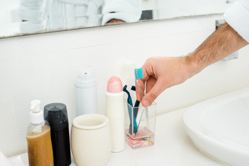 close up male hand and different toiletries in bathroom