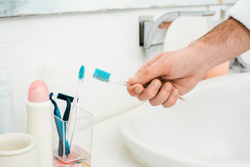 cropped view of male hands adding toothpaste on toothbrush