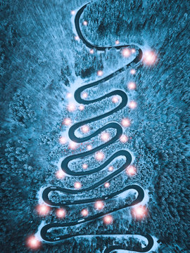Christmas background with mountain road through the forest. Aerial view of road during snowy winter