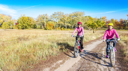 Fototapeta premium Family on bikes autumn cycling outdoors, active mother and kid on bicycles, aerial view of happy family with child in fall park from above, sport and fitness concept 