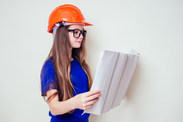 Teenager girl with plan holding urban designer paper in a construction helmet hard hat and glasses
