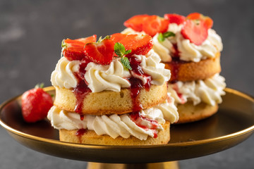 Victoria sponge cake with strawberries, jam and whipped cream on dark background. Copy space.