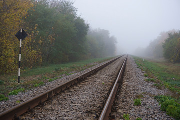 Fototapeta premium Railway arrow in the thick fog in the autumn, the concept of decision making in conditions of uncertainty.