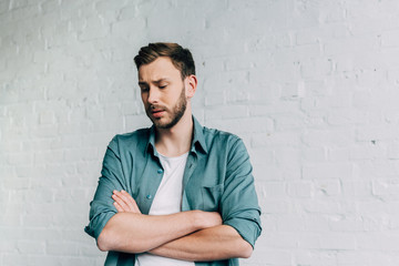 selective focus of upset man standing with crossed arms