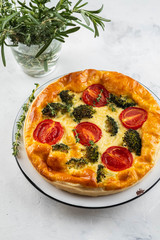 Vegetable pie quiche with broccoli, tomatoes and soft cheese on white background.