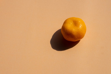  a whole oranges with strong shadow on orange background, copy space