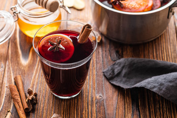 Hot mulled wine with spices, citrus and honey on woodern background. Copy space.