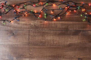 String of colorful lights. Christmas background concept. Border and copy space, wooden boards,...