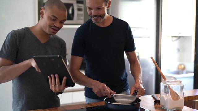 Gay Couple Making Tapioca - Brazilian Food and Using Tablet at Kitchen