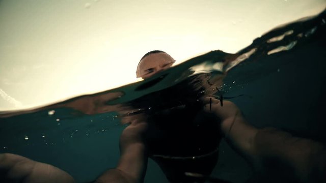 Selfie of man swimming on water surface with sunset sun at background, gopro dome shot