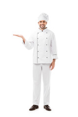 smiling young chef pointing at blank space and looking at camera isolated on white