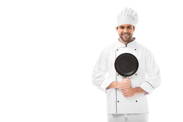 happy young chef holding frying pan and looking at camera isolated on white