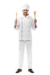 smiling young chef holding kitchen utensils and looking at camera isolated on white