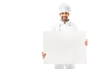 handsome young male chef holding blank banner and smiling at camera isolated on white