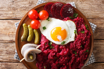 traditional Labskaus recipe of potato, corned beef and beet with a fried egg and herring close-up...