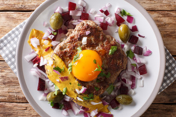 Danish cuisine: Parisian steak or Pariserbof with vegetables and mustard close-up on a plate....