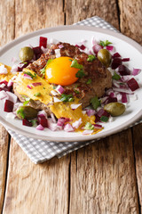 Fried Beef Tartare or Parisian Steak - Pariserbof with egg,  vegetables and mustard close-up on a plate. vertical