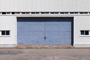 Fototapeta na wymiar Blue gate in white metal warehouse wall