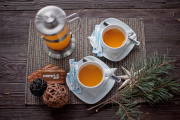 sea-buckthorn tea with two cups and a teapot on a table