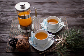 sea-buckthorn tea with two cups and a teapot on a table