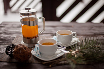 sea-buckthorn tea with two cups and a teapot on a table
