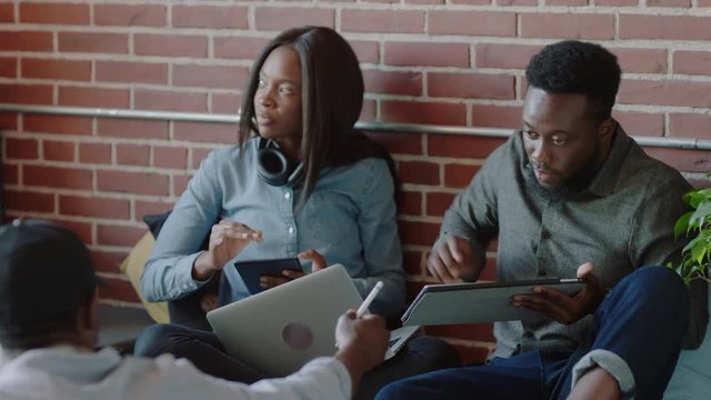 young african american business team using mobile computer technology brainstorming sharing development ideas students relaxing studying in startup company office