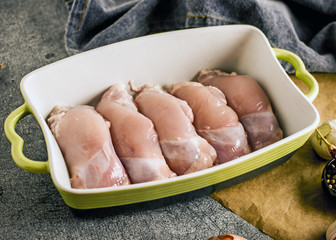Fototapeta na wymiar Raw Free range Boneless skinless chicken thighs with spices in a baking dish