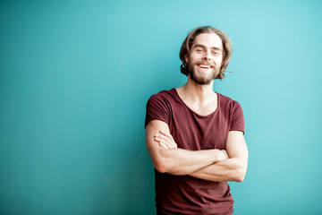 Portrait of a young caucasian bearded man with long hair dressed in t-shirt on the colorful background