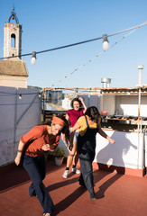 Gorgeous Hispanic women dancing synchronically standing outdoors at old shabby buildings and laughing on sunny summer day