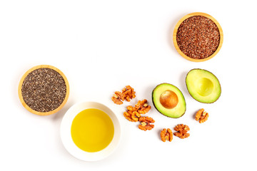 An overhead photo of healthy omega-3 vegan diet food. Avocado, nuts, chia seeds, and flaxseeds, shot from the top on a white background with copy space