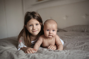 older sister and naked baby 5 months on bed