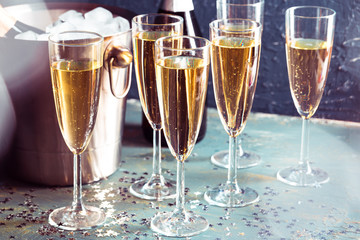 Champagne bottle in bucket with ice and glasses of champagne