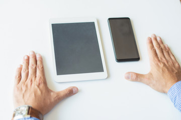 Closeup of business man with smartphone and tablet computer. Business man using digital devices at desk. Technology and communication concept. Cropped view.