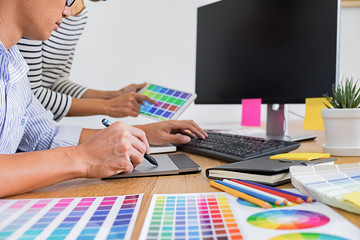 Graphic design with color swatches and tablet on a desk. Graphic designer drawing something on...