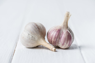 Two garlic heads on white wooden table