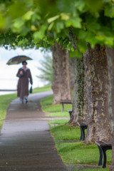 Frau mit Schirm auf Weg unter Bäumen