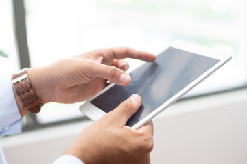 Close-up of busy man holding tablet and working with online data. Unrecognizable manager viewing information and editing data. Planning concept