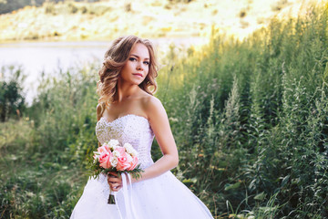 Photo of the bride in nature with a beautiful bouquet of flowers