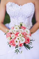 Bride in white dress holds wedding bouquet in hands