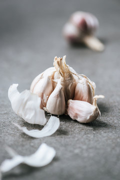 peeled bulb of garlic with husk on grey marble table