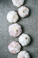 Row of ripe whole garlic bulbs on grey background